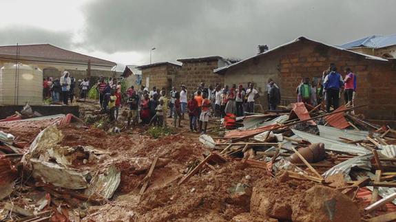 Residentes observan los daños a sus viviendas tras un deslizamiento de tierra producido por las fuertes lluvias en el suburbio de Regent, detrás del embalse de Guma, cerca de la capital Freetown.