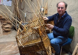 El artesano en su taller, con la reparación de un sillón de mimbre