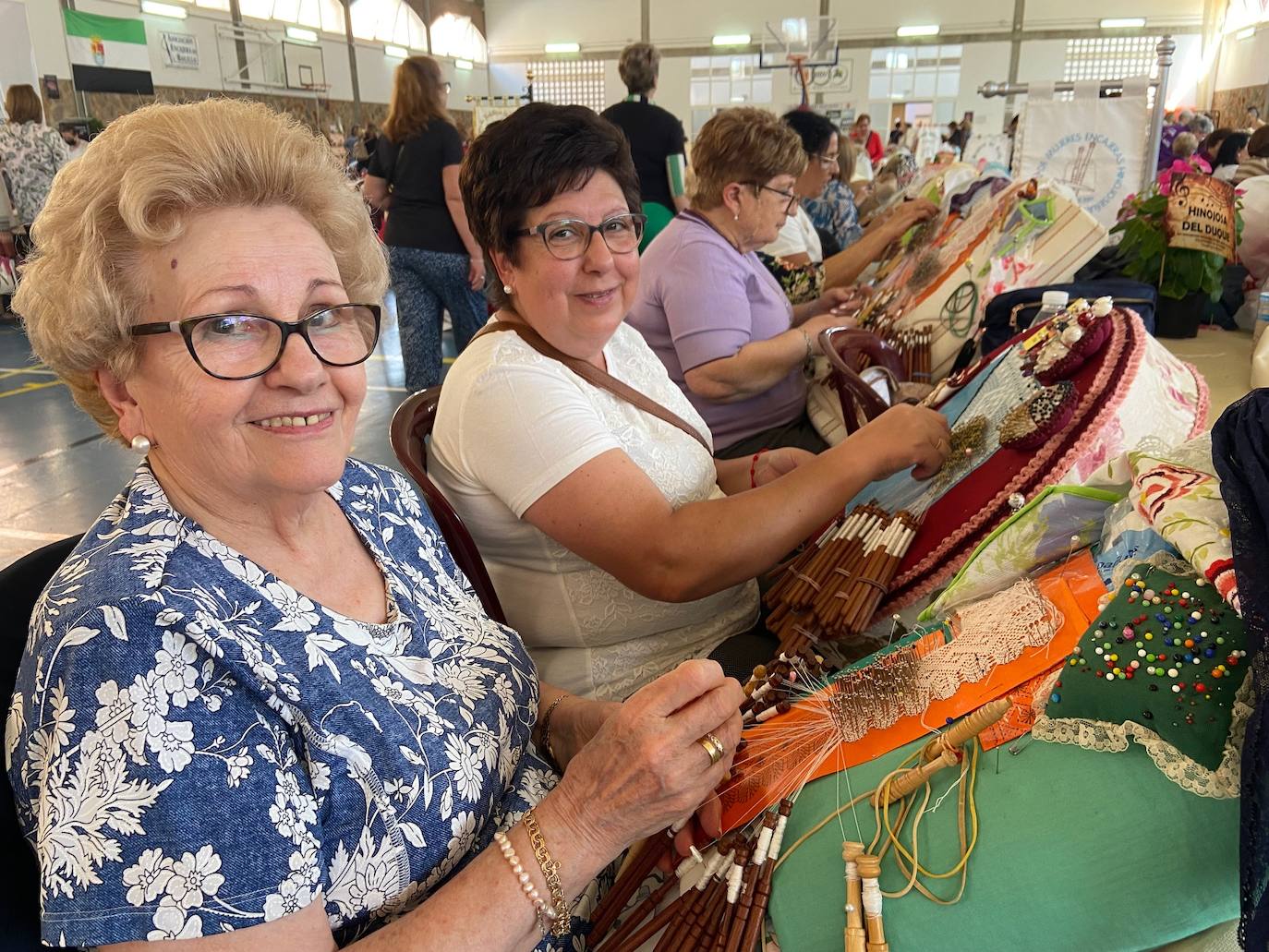 Dos encajeras de bolillos realizan sus labores en la feria de Villafranca.
