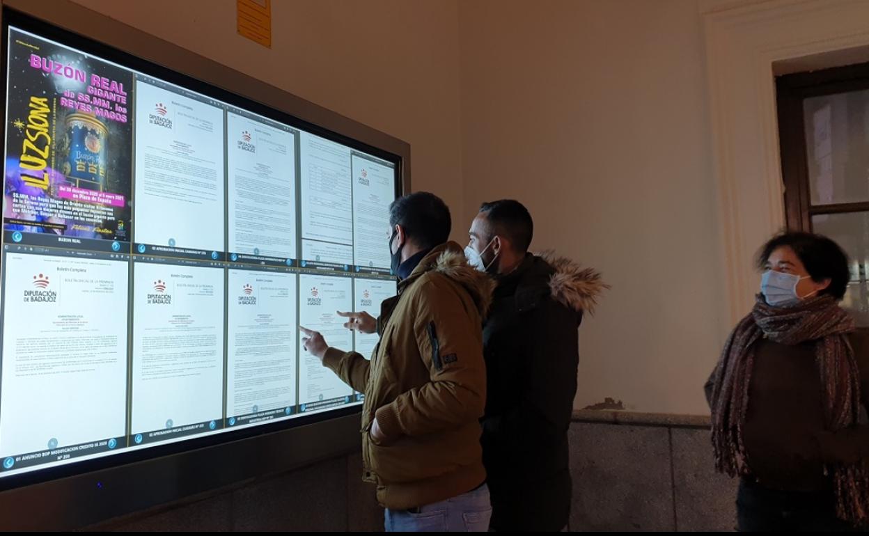 Ciudadanos consultan el tablón de anuncios del ayuntamiento de Villanueva de la Serena. 