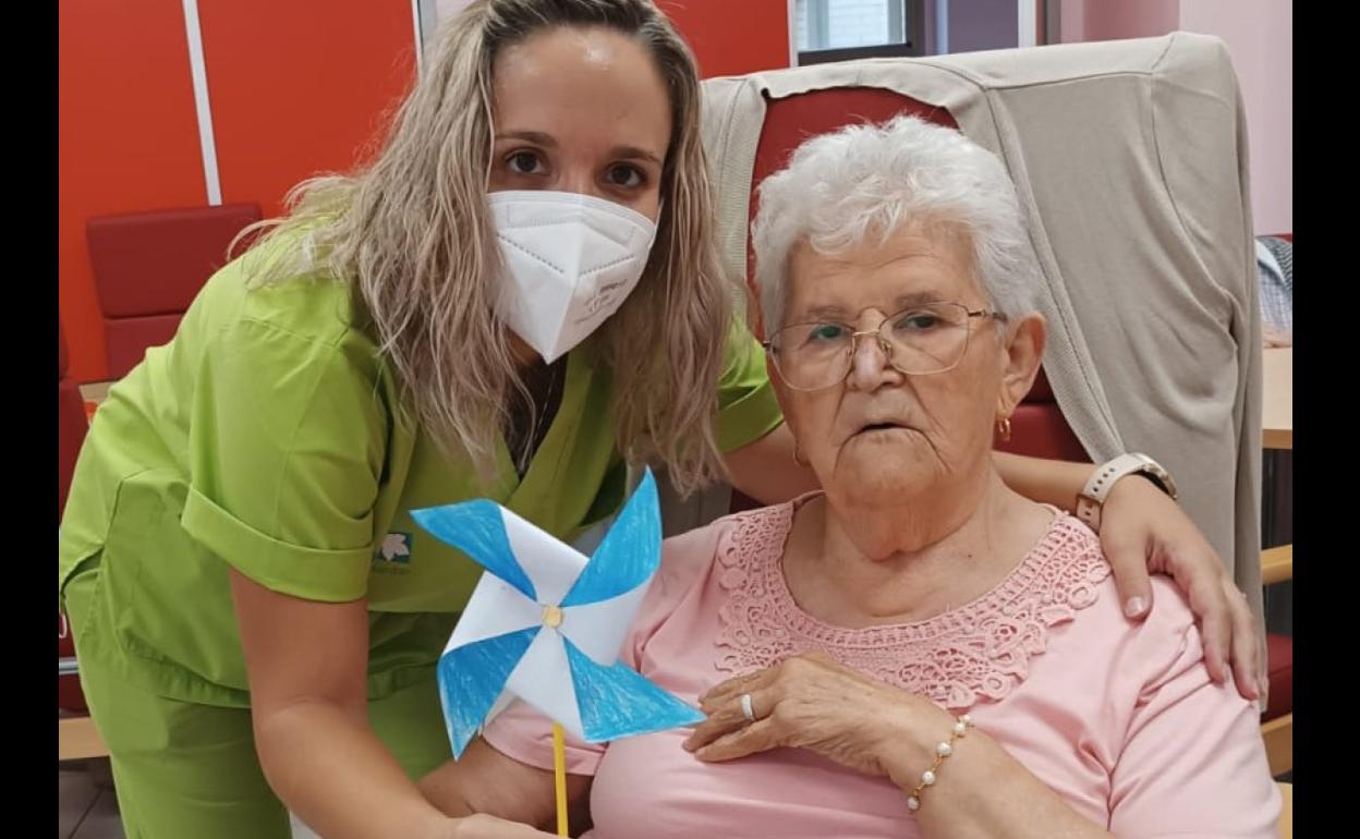 Una técnico realiza un taller de terapia ocupacional con una mujer afectada con alzheimer. 