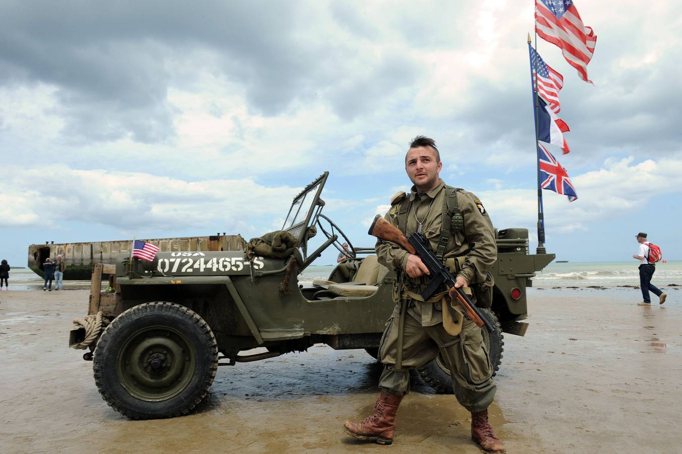 Un hombre francés vestido con ropa militar de época posa junto a un viejo jeep militar americano en la playa en Arromanches-les-Bains. AFP PHOTO / JEAN FRANCOIS MONIER