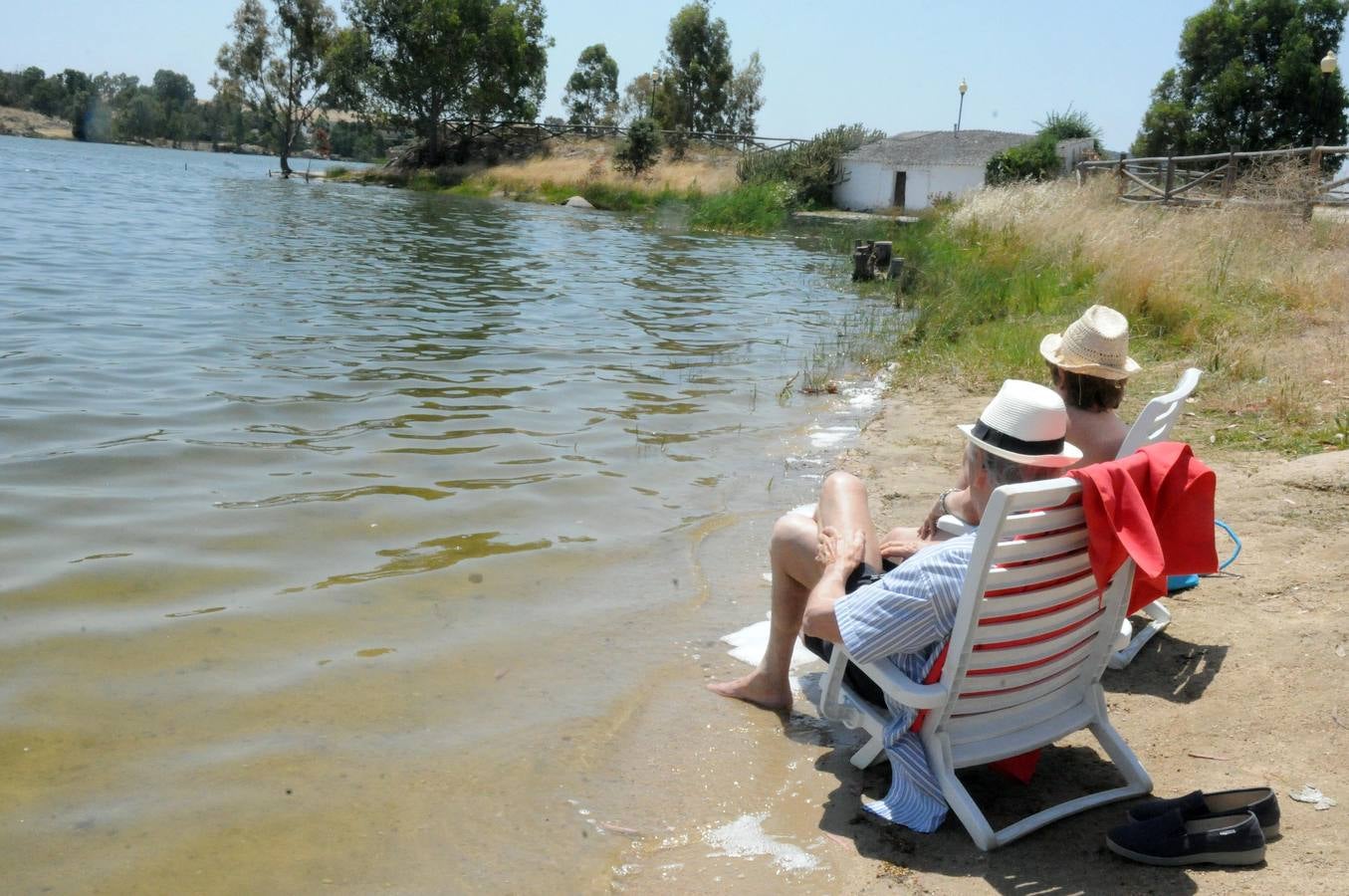 Dos personas sentadas en sus butacas en la orilla del lago Proserpina en Mérida. Foto: Brígido Fernández