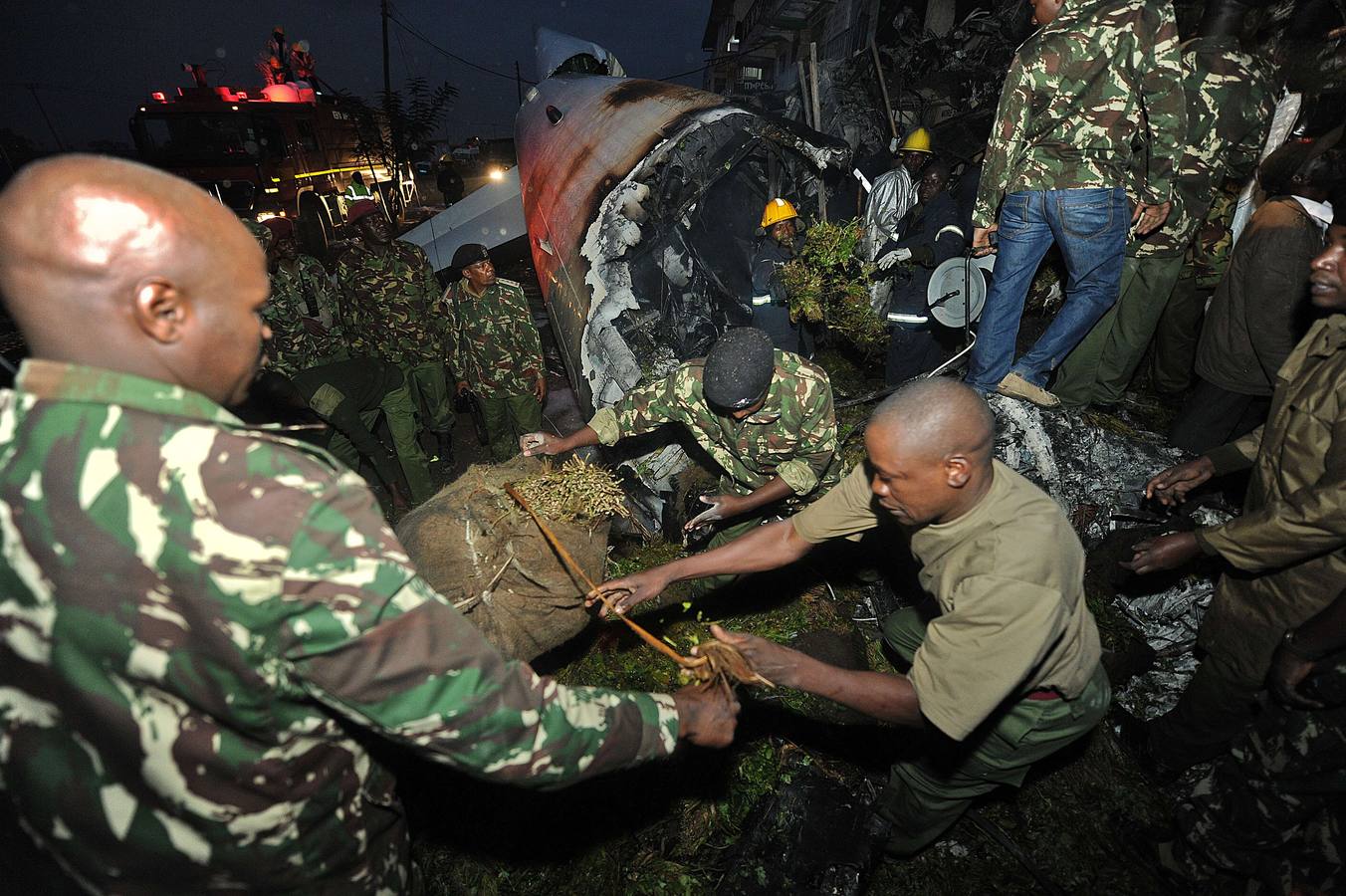 Miércoles, 2 de julio. Oficiales de la Policía inspeccionan la escena del accidente del avión de carga de la ONU que se estrelló en un suburbio de Nairobi (Kenia) minutos después de despegar el Aeropuerto Internacional Jomo Kenyatta, rumbo a Somalia. En el accidente murieron cuatro personas. EFE / Dai Kurokawa