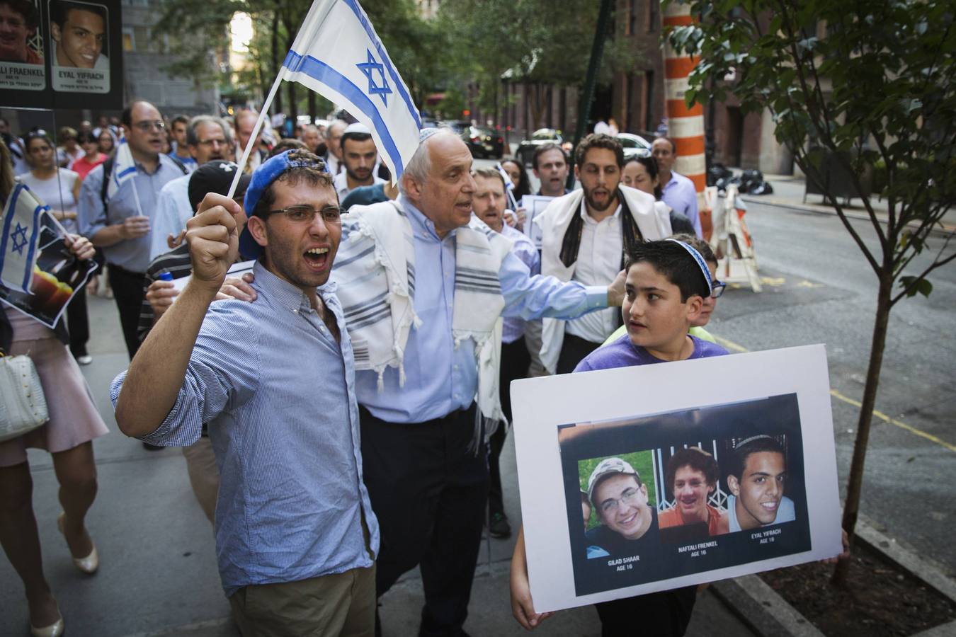 Martes, 1 de julio. El Rabino Avi Weiss habla en medio de los manifestantes durante una ceremonia en memoria de los tres adolescentes israelíes desaparecidos cuyos cuerpos fueron encontrados en la ocupada Cisjordania, cerca de la sede de las Naciones Unidas. Varios cientos de personas ondeando banderas israelíes y expresando dolor y solidaridad realizaron una vigilia en Nueva York después de que los cuerpos de Eyal Yifrach, 19, Gilad Shaar, 16 y Naftali Fraenkel, 16, fueran encontrados en un campo cerca de Hebrón, no lejos de un camino en el que se creía que habían sido secuestrados mientras hacían autostop el 12 de junio. REUTERS / Lucas Jackson