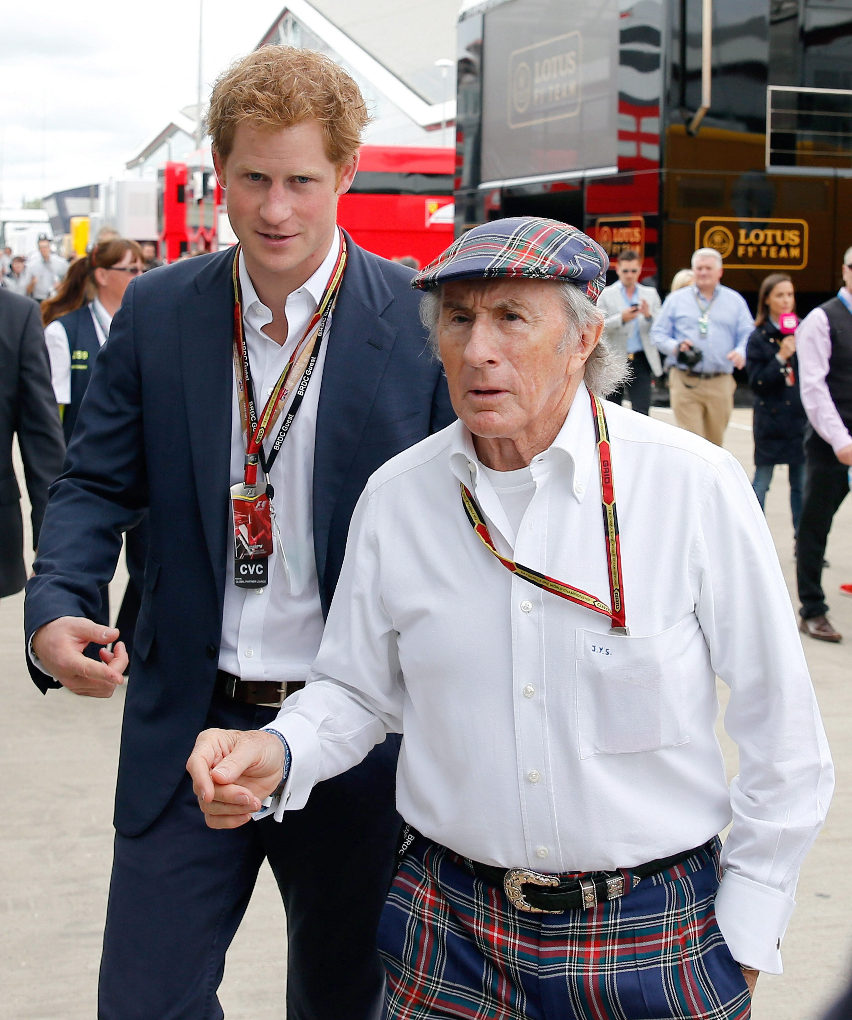 La leyenda británica de la Fórmula 1, Jackie Stewart (d), pasea por el paddock junto al Príncipe Harry (i).