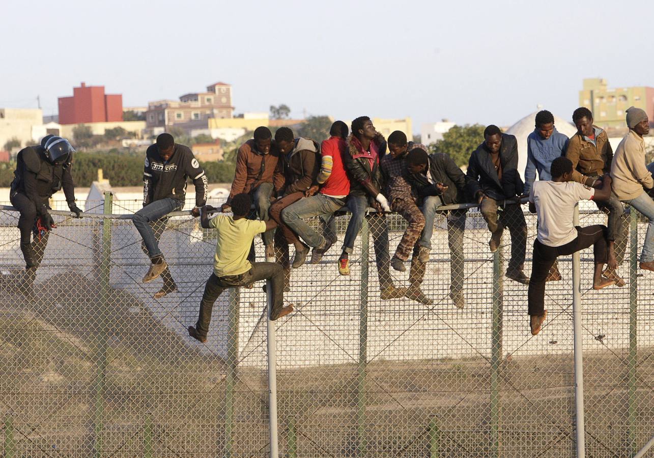 Decenas de inmigrantes encaramados en la valla fronteriza de Melilla