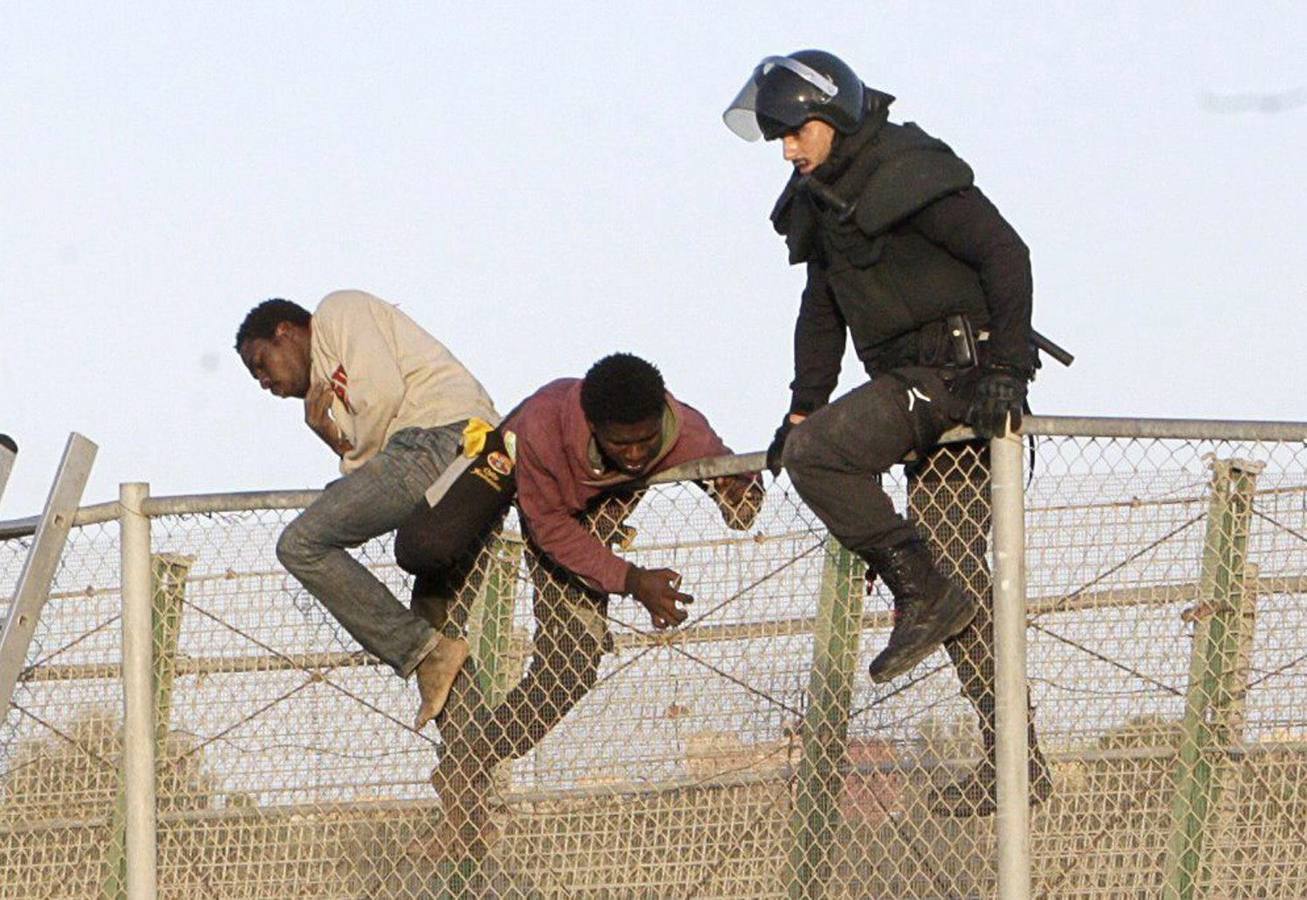 Decenas de inmigrantes encaramados en la valla fronteriza de Melilla