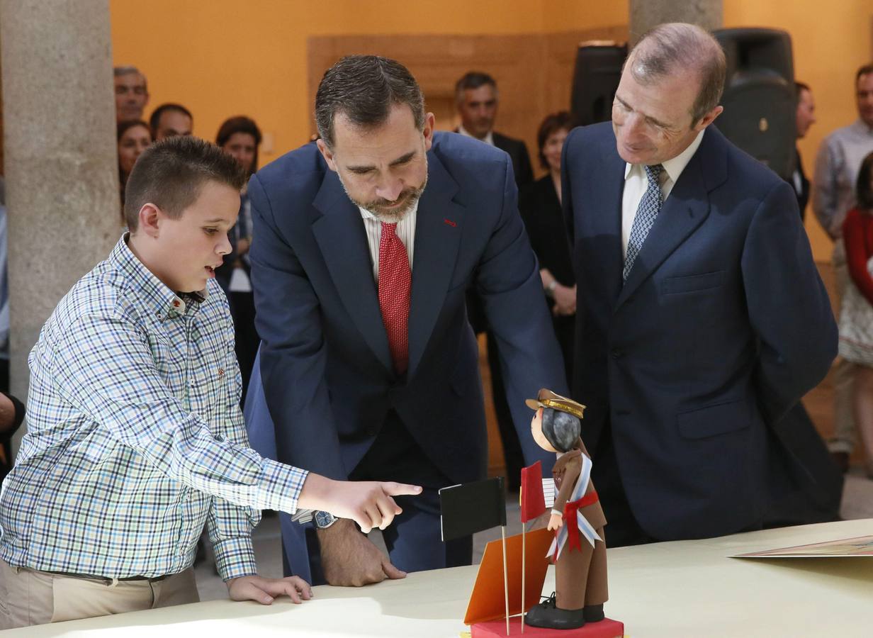 El rey Felipe VI observa el trabajo de una de las niños ganadoras de la XXXII y XXXIII ediciones del concurso escolar '¿Qué es un Rey para ti?'.