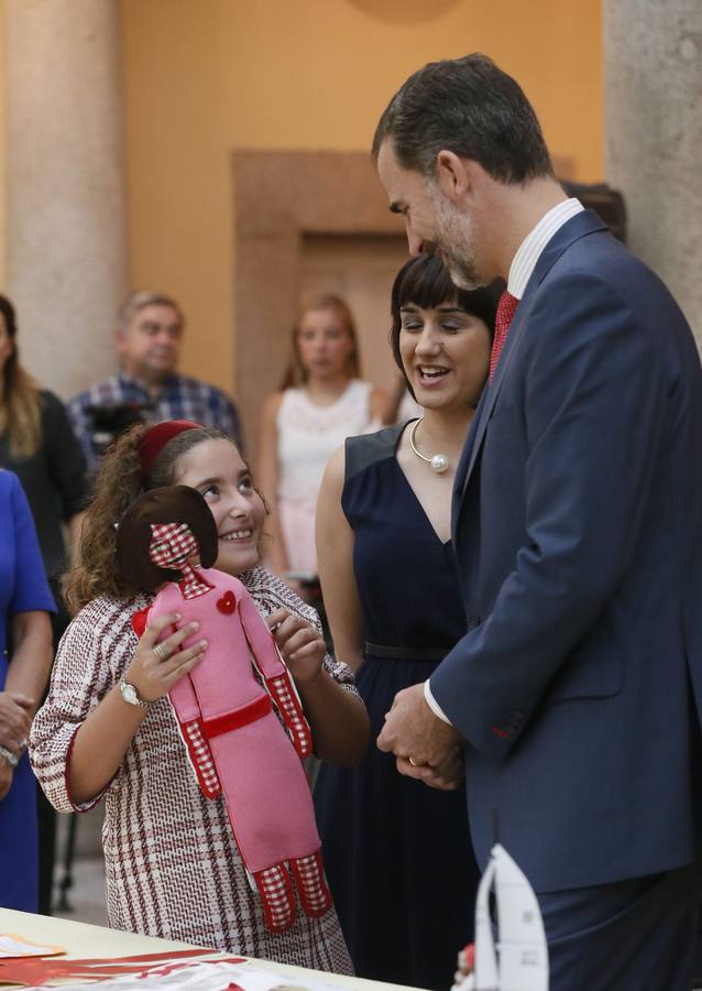 El rey Felipe VI observa el trabajo de una de las niñas ganadoras de la XXXII y XXXIII ediciones del concurso escolar '¿Qué es un Rey para ti?'.