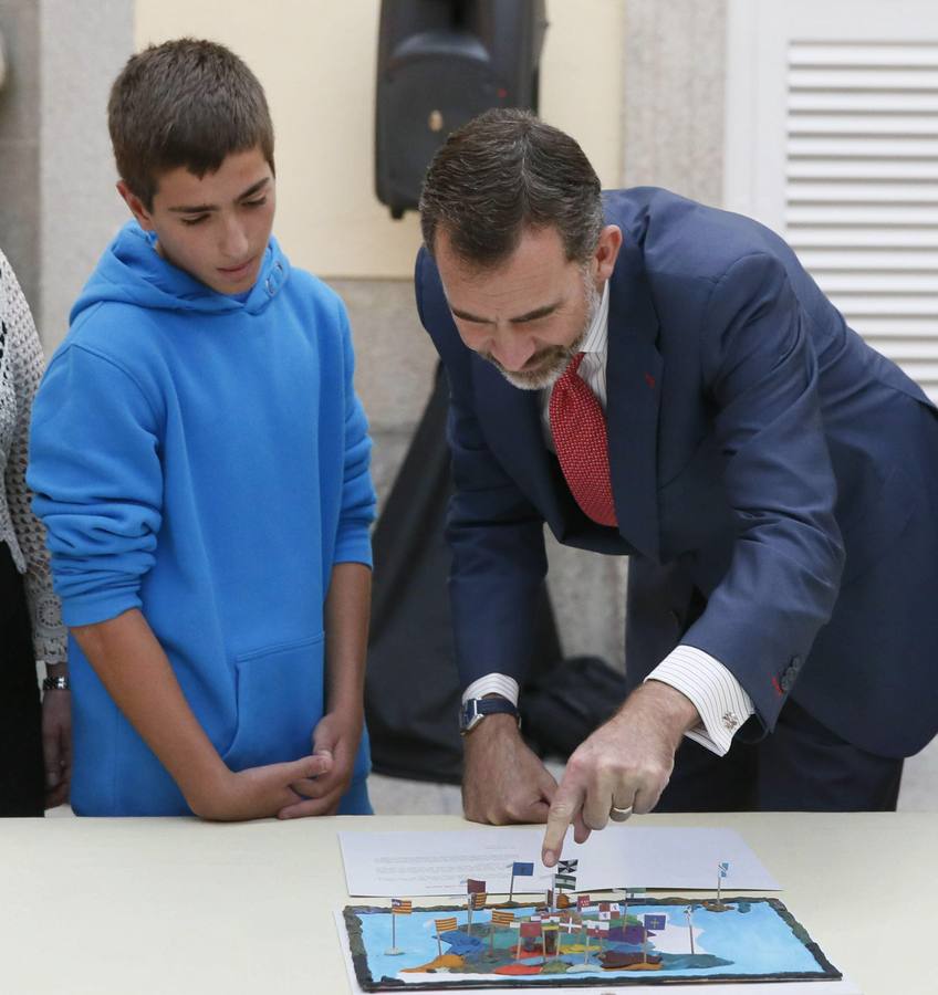 El rey Felipe VI observa el trabajo de una de las niñas ganadoras de la XXXII y XXXIII ediciones del concurso escolar '¿Qué es un Rey para ti?'.