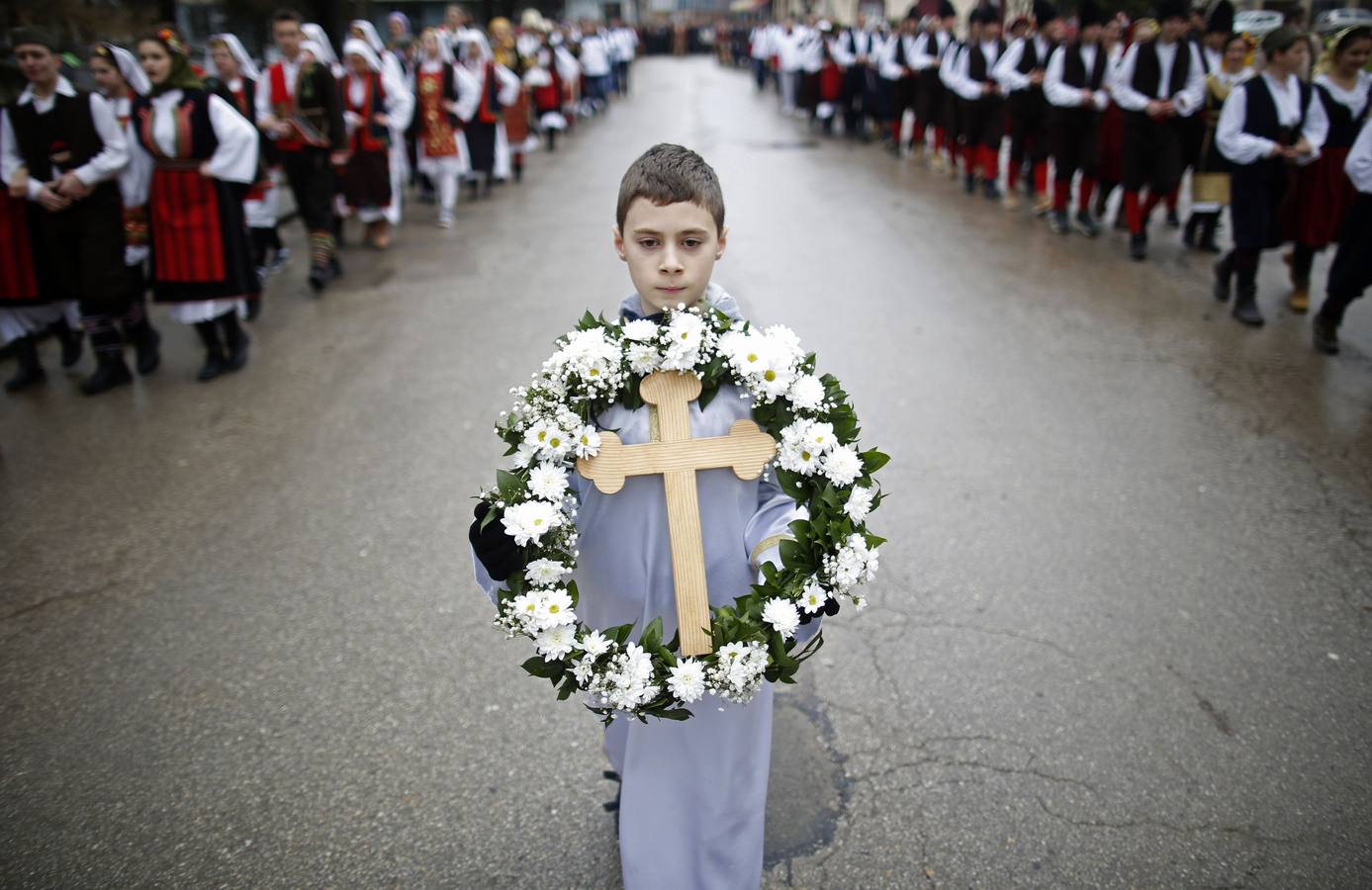 Un niño lleva una cruz durante las celebraciones en Prijedor (Bosnia y Herzegovina). Los sacerdotes ortodoxos bendicen las aguas lanzando una cruz. Los creyentes intentan recuperarla como si de una competición se tratara ya que según las creencia la captura del símbolo tra salud y prosperidad a quien la atrapa. Fotografía: REUTERS-Dado Ruvić.