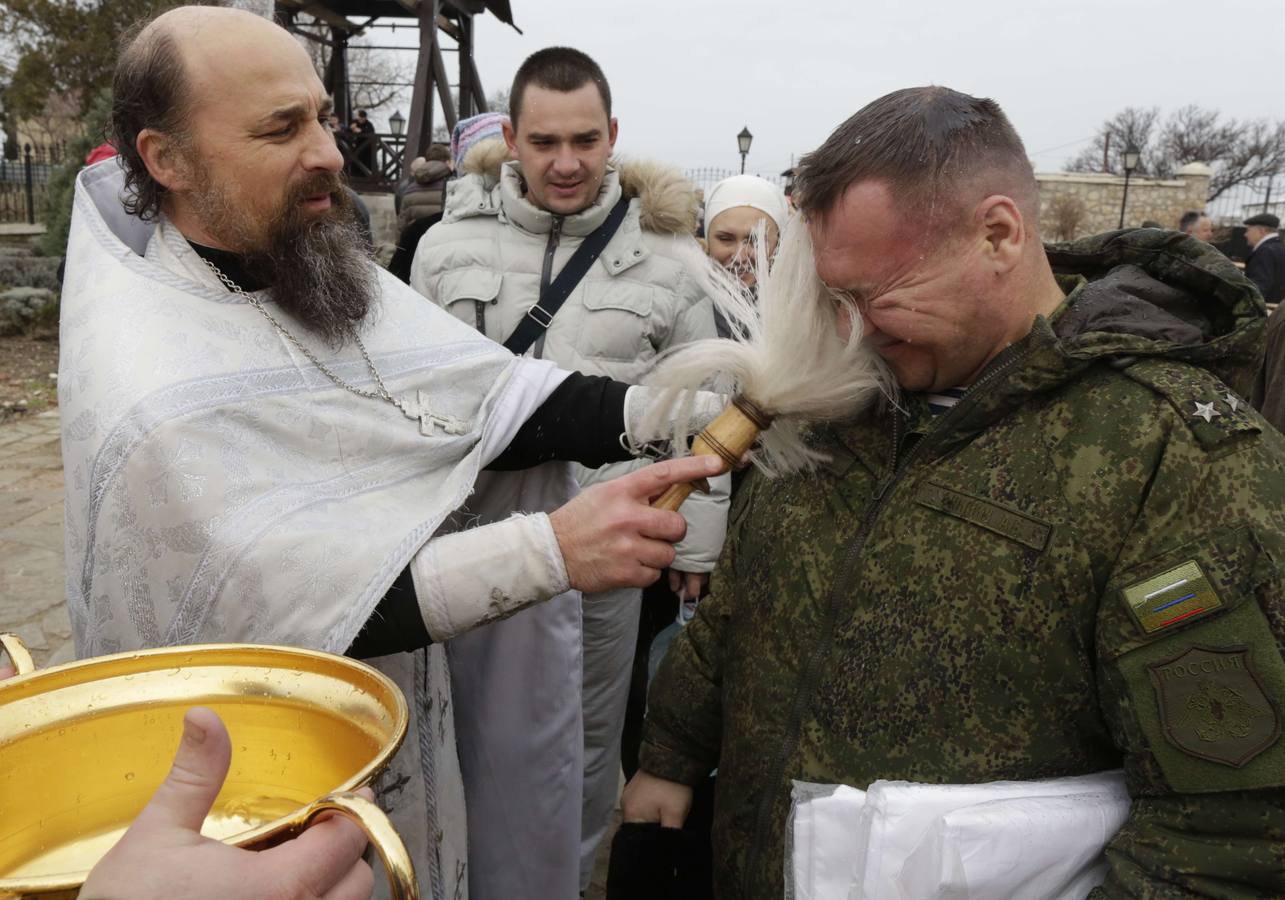 Un sacerdote ortodoxo rocía agua bendita en un fiel, durante la celebración de la festividad de la Epifanía a las afueras de Sebastopol. Fotografía: AFP-Max Vetrov