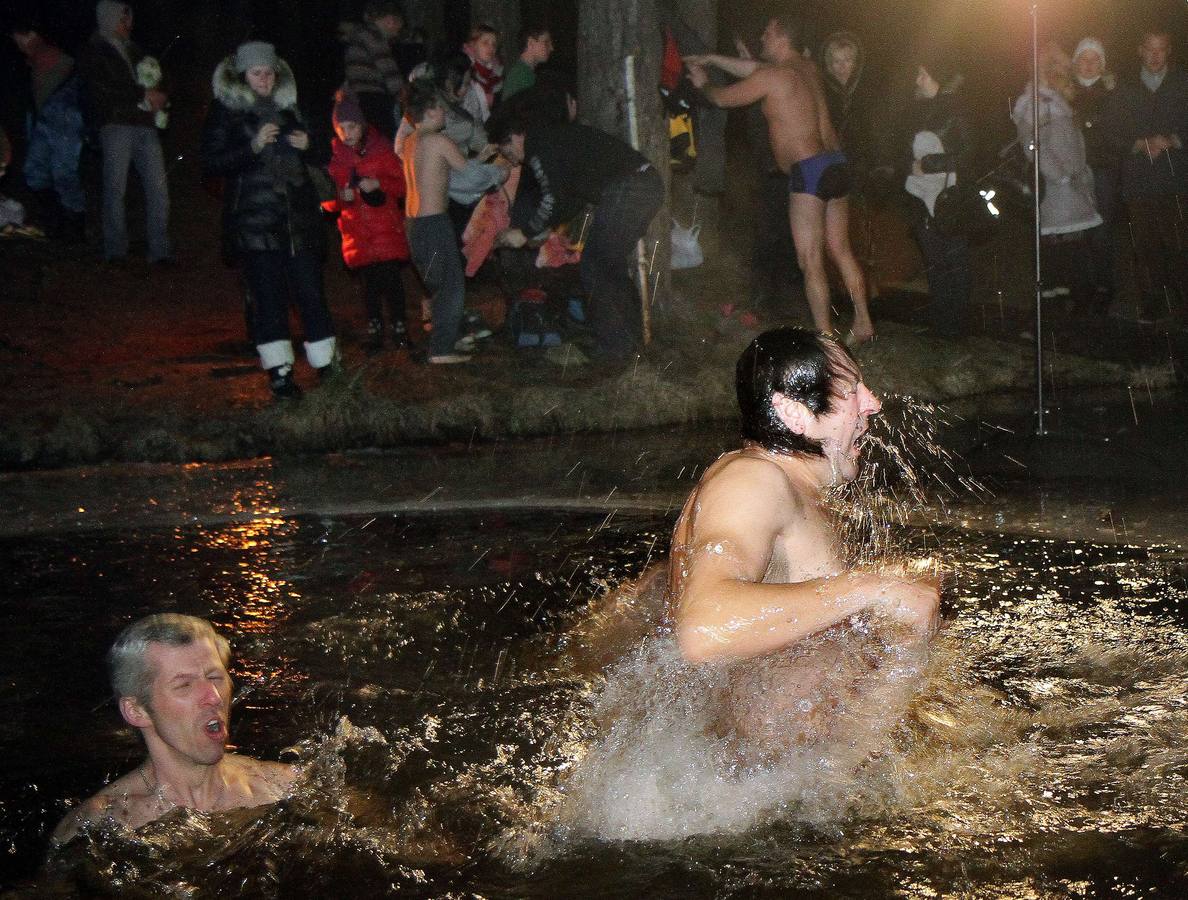 Algunas persona toman un baño en un agujero realizado en el hielo de un lago congelado en Vilnius, para celebrar la Epifanía ortodoxa rusa. Fotografía: AFP-Petras Malukas