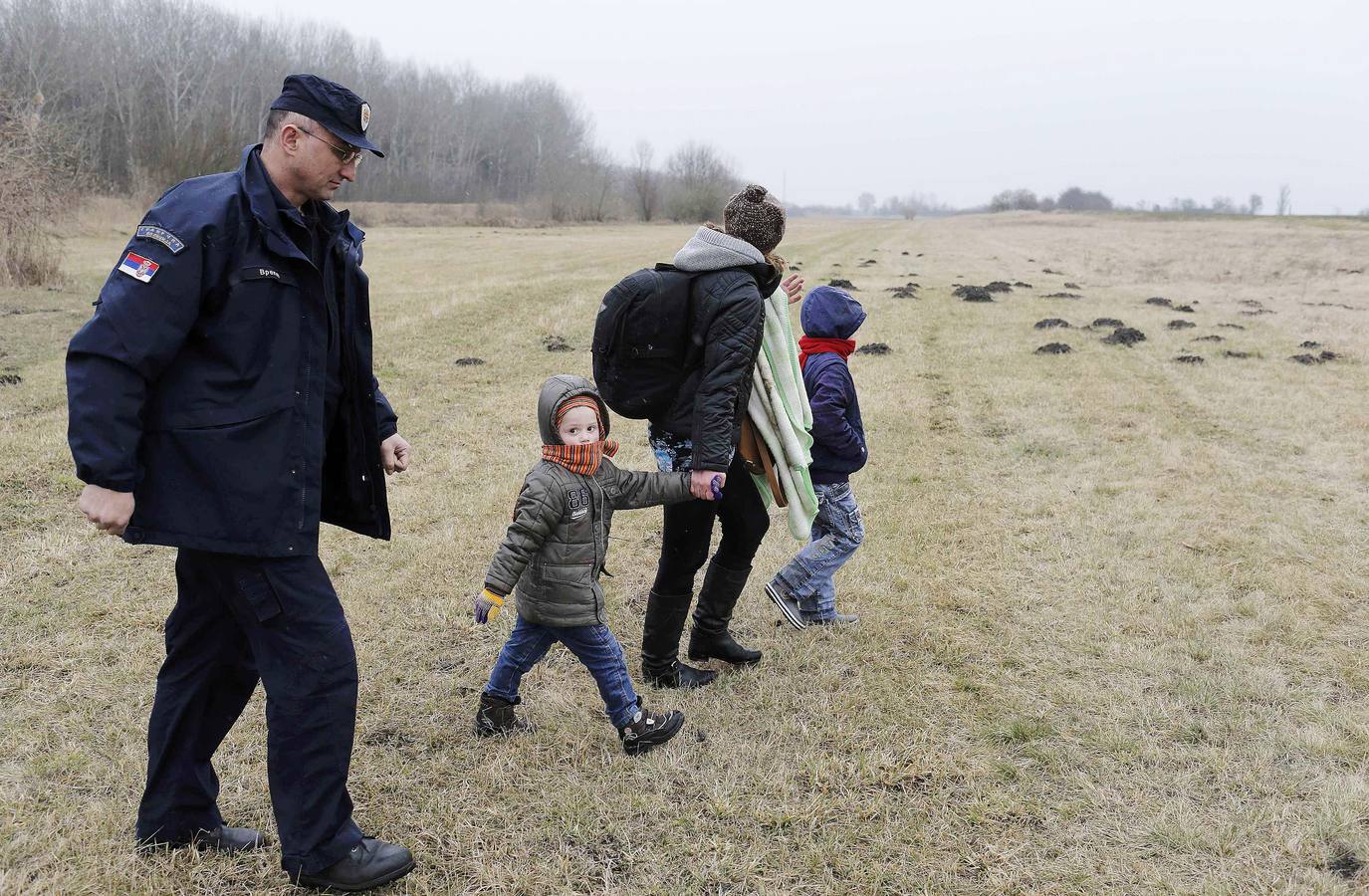Una mujer kosovar sostiene a su hijo antes de montarse en un vehículo de la policía de fronteras de Serbia tras ser detenidos cerca de la ciudad de Subotica. al tratar de intentar pasar ilegalmente a Hungría. Fotografía: REUTERS / Marko Djurica