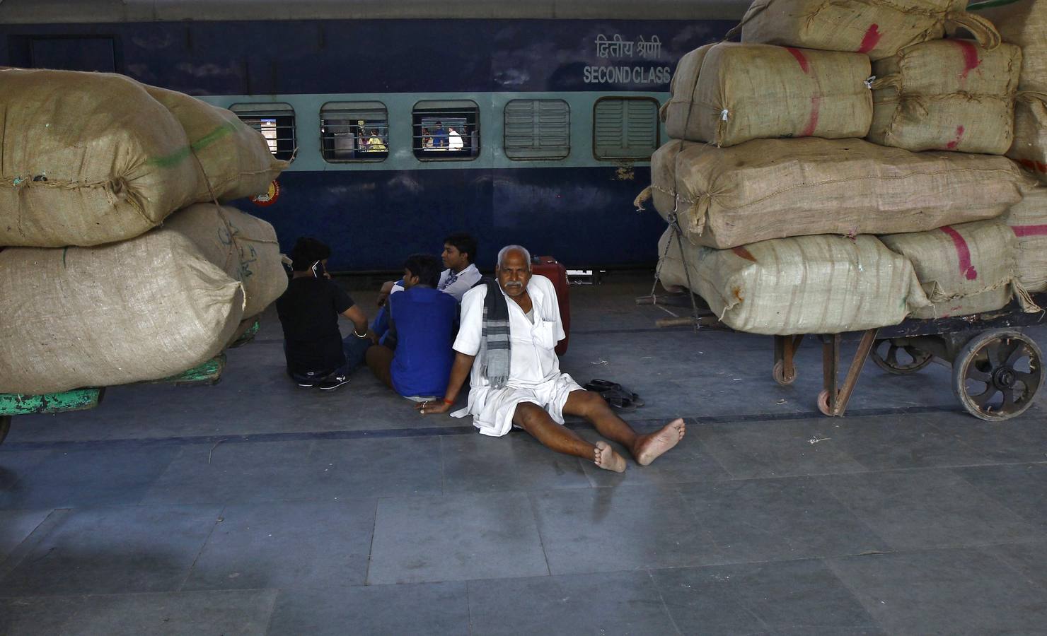 Pasajeros esperan sentados en el andén de la estación de Calcuta a que llegue su tren.