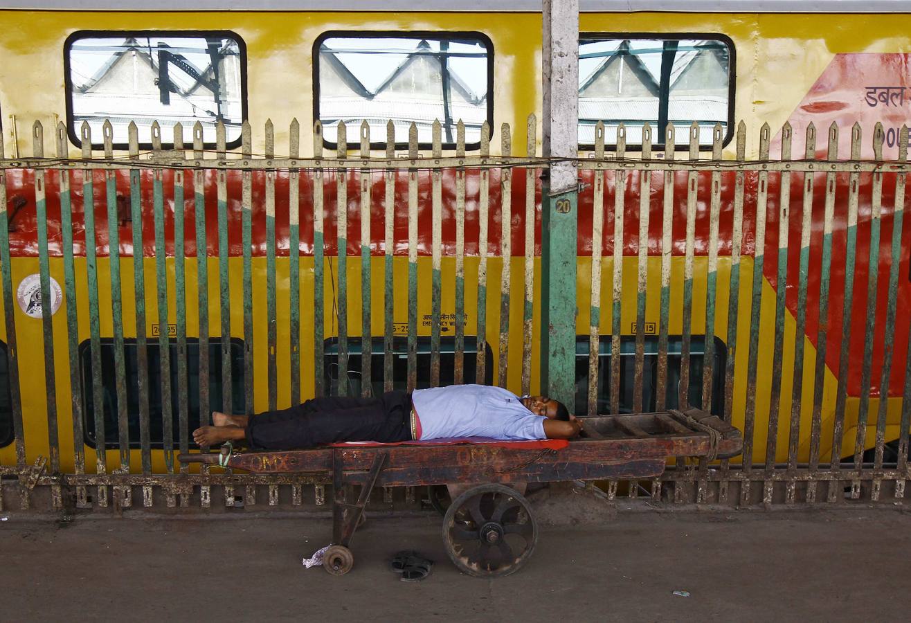 Un hombre duerme en la carretilla de transporte maletas en la estación de Calcuta