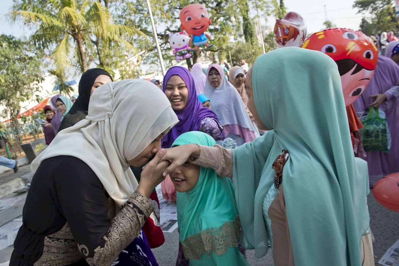 Una mujer indonesa besa las manos de un anciano, una práctica tradicional para rendir homenaje, después de las oraciones durante las celebraciones del Eid al-Fitr en el puerto de Sunda Kelapa en Yakarta