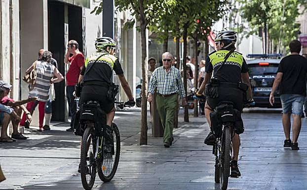 Dos agentes patrullan la calle Menacho en bicicleta.