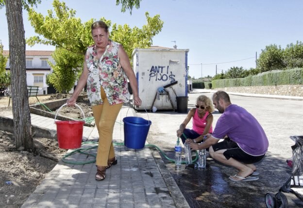 Los vecinos cargan con cubos de agua que sacan de una fuente pública. :: l. cordero