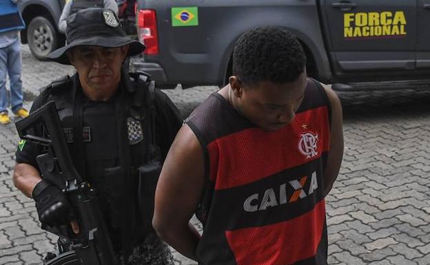 Un policía escolta a un detenido en Río. 