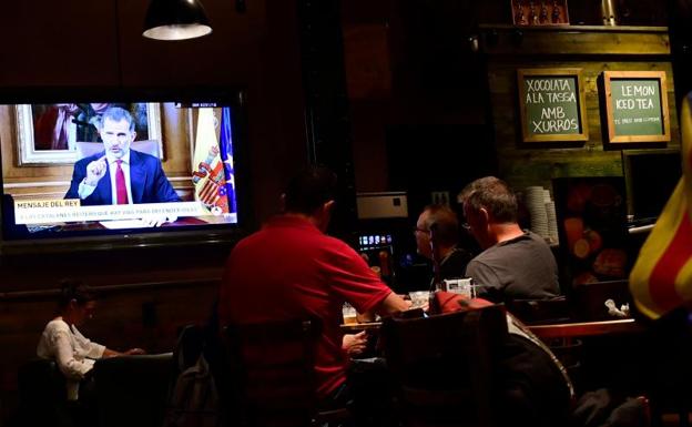 Clientes siguen el mensaje del Rey en un bar de Barcelona.