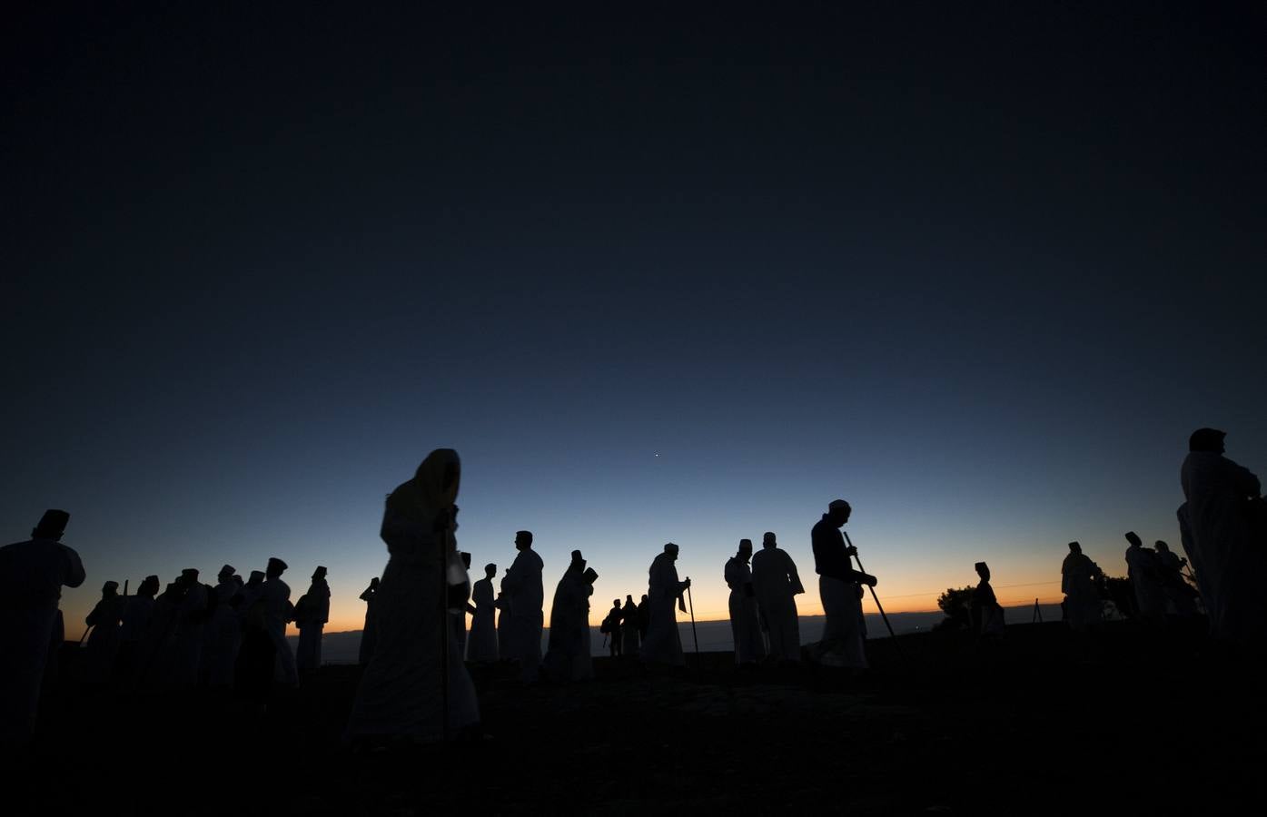 Miembros de la comunidad samaritana caminan hacia la cima del Monte Guerizín al amanecer en Nablus (Palestina), con motivo de la celebración del Sukot o fiesta de los tabernáculos.