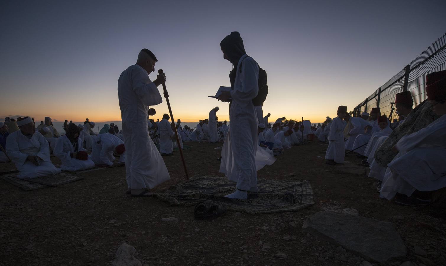 Miembros de la comunidad samaritana caminan hacia la cima del Monte Guerizín al amanecer en Nablus (Palestina), con motivo de la celebración del Sukot o fiesta de los tabernáculos.
