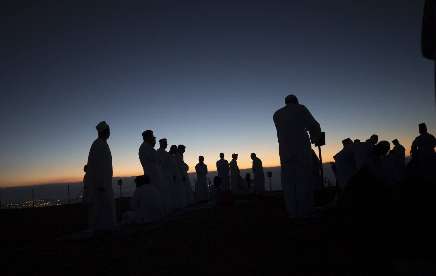 Miembros de la comunidad samaritana caminan hacia la cima del Monte Guerizín al amanecer en Nablus (Palestina), con motivo de la celebración del Sukot o fiesta de los tabernáculos.