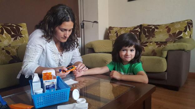 Una madre realiza a su hija la prueba para medir la glucosa. :: r. C.