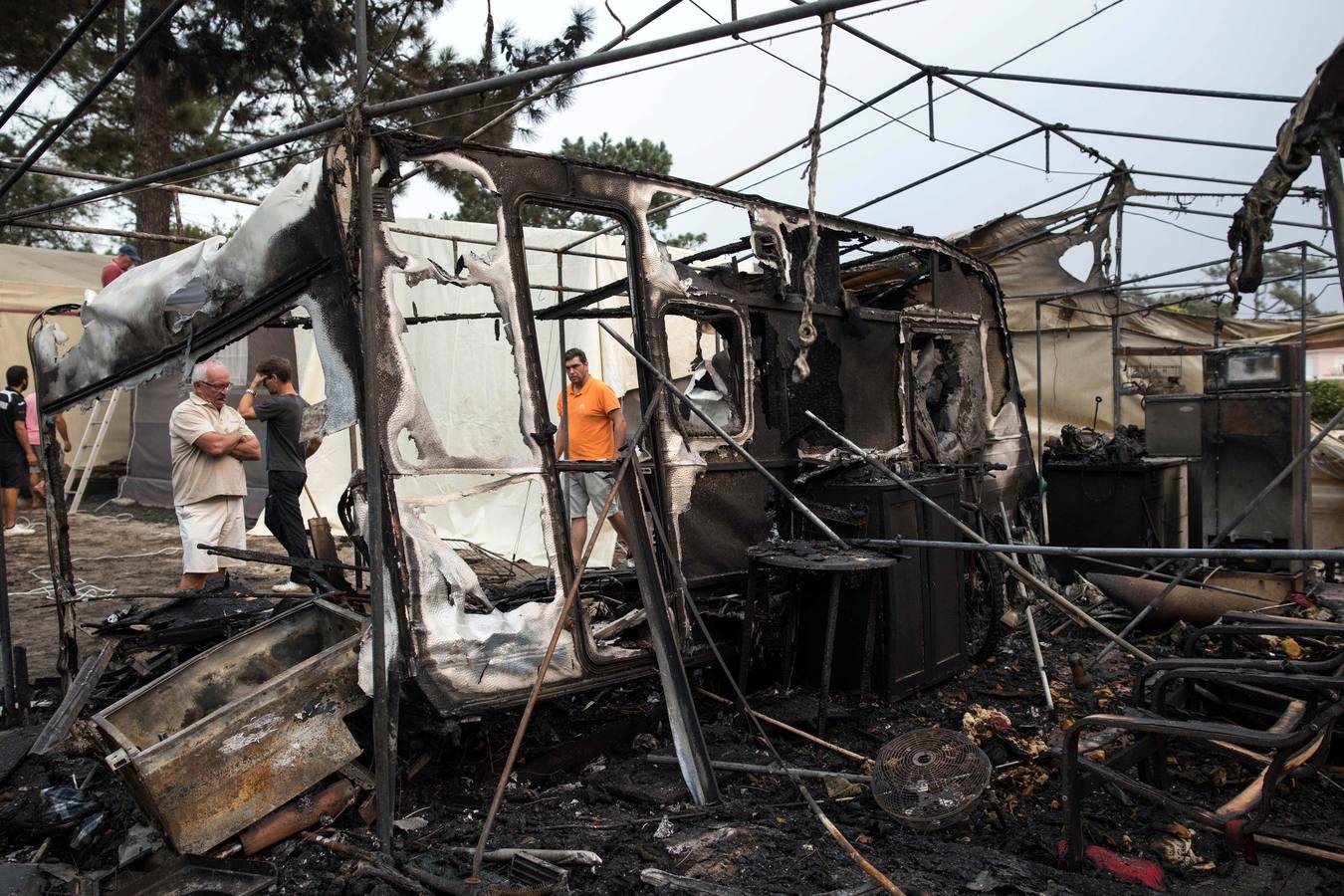 Vecinos observan los daños tras un incendio forestal en un camping en Marinha Grande, en el centro de Portugal,