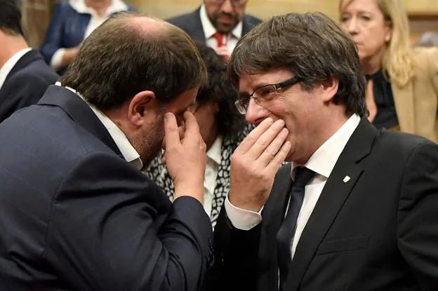 El gesto. Carles Puigdemont, a la derecha, y Oriol Junqueras dialogan tapándose la boca para que nadie pueda leer sus labios