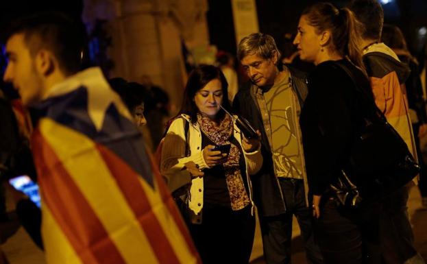 Varios independentistas escuchan su móvil tras una manifestación en Barcelona. 