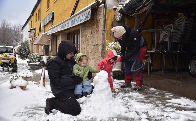 Unos padres juegan con sus hijos en la nieve al lado de la N-110, Tornavacas