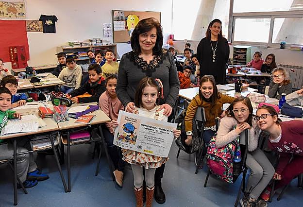 Carlota Sánchez Molina y su profesora Inés Fernández junto a sus compañeros de clase. Abajo, imagen de su cartel, que ha sido premiado en la categoría de 7 a 12 años. :: c. moreno