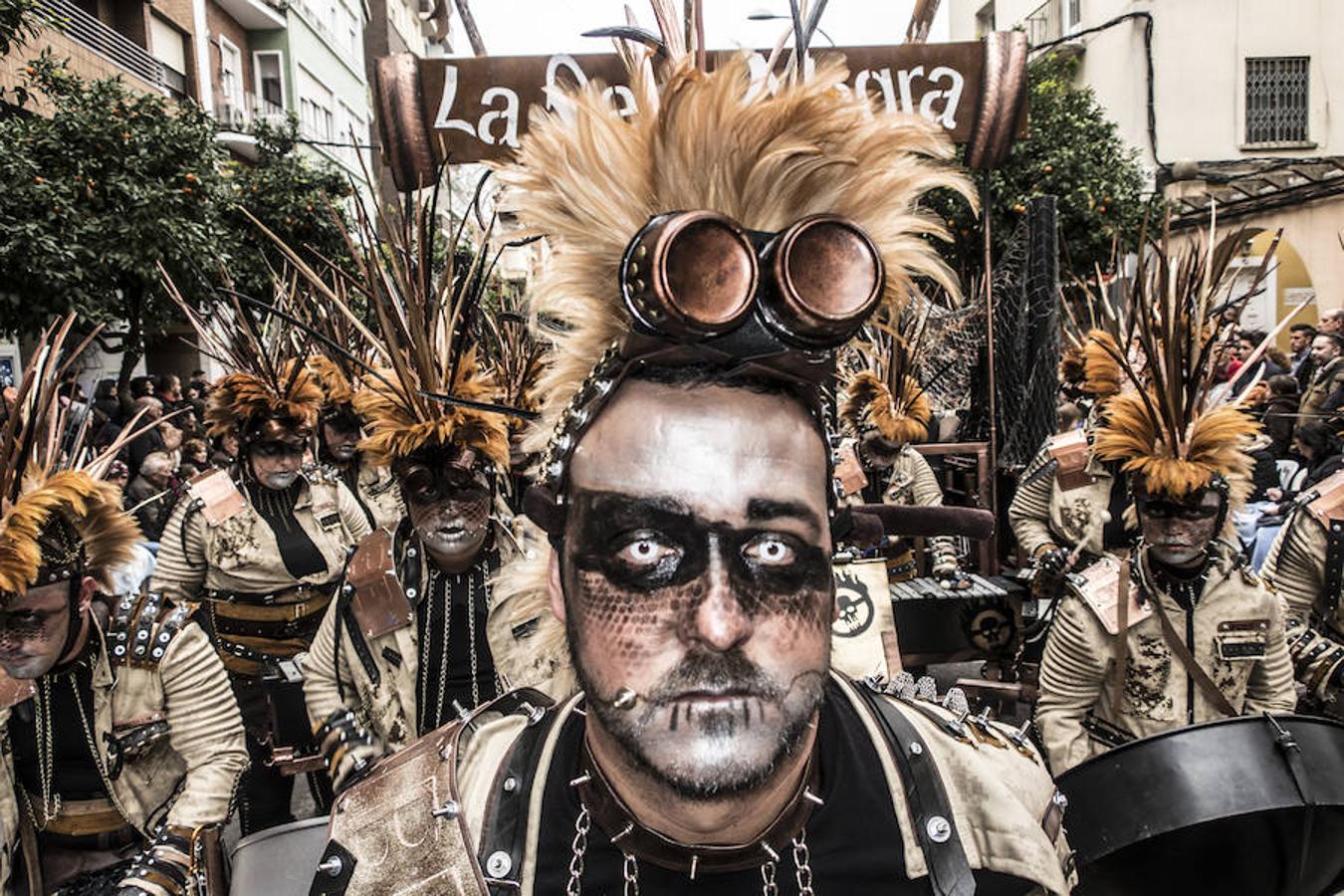 Caribe presenta una alegoría de la película 'Mad Max'. Los integrantes de esta comparsa llevan un disfraz de tonos negros, marrones, beiges y motaza. También han usado tela de camuflaje