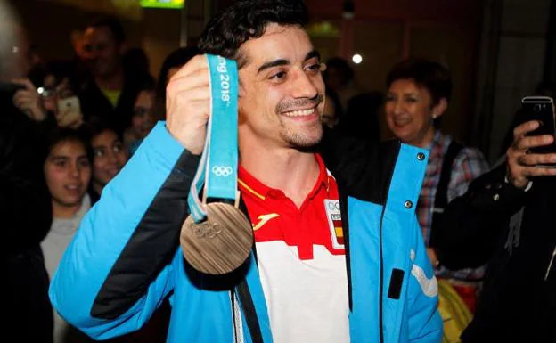 Javier Fernández muestra su medalla a su llegada al aeropuerto Madrid Barajas.