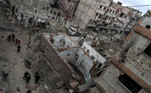 Vecinos inspeccionan los edificios en ruinas después de varios bombardeos en Duma, feudo rebelde de Guta Oriental (Siria).