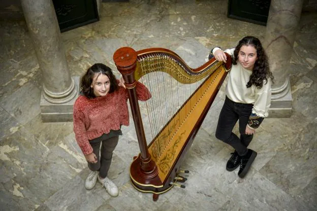 Fernanda Guijarro, a la izquierda, y Carolina Rodríguez en el Conservatorio de Música Juan Vázquez de Badajoz junto a un arpa. :: j. v arnelas