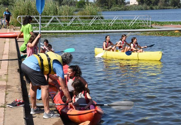 Monitores y voluntarios ayudando ayer a disfrutar del río sobre canoas. A la derecha, un joven sobre una tabla de paddle surf esquivando una alfombra de nenúfar Moreno