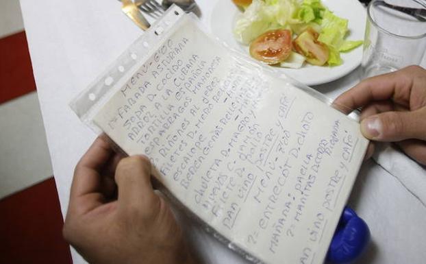 Unos clientes leen un menú en un restaurante madrileño. 