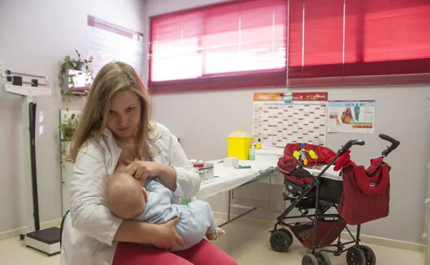 Una enfermera dando el pecho a su hijo en su consulta del centro de salud de Valdepasillas.