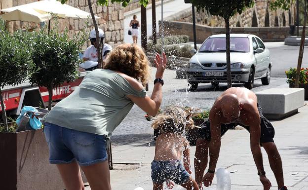 Una familia de Granada se refresca en una fuente de Mérida