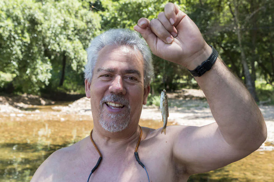 Antonio Torres, jubilado de Talavera La Real que ha regresado a su pueblo tras 43 años trabajando en Cataluña, muestra el pez que acaba de capturar en una de las tres piscinas naturales de La Codosera.