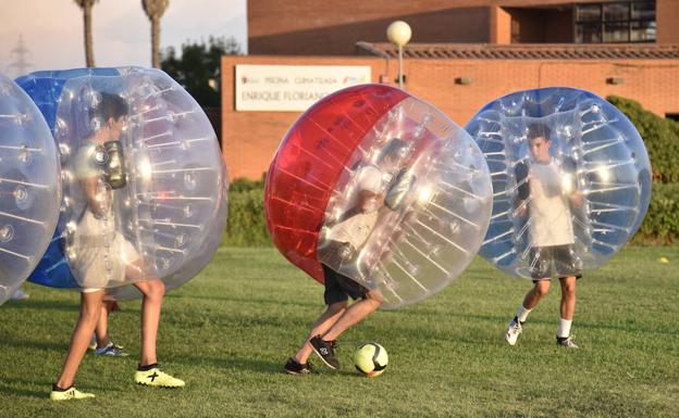 Varios chicos practican el fútbol burbuja en el campo de césped de la Granadilla.