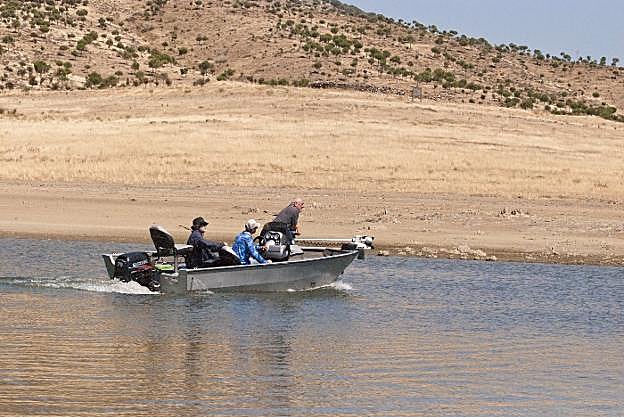 Denis y Thierry, dos amigos galos, salen a pescar guiados por el extremeño Zoilo Montero (en el centro de la lancha), en La Serena. :: A.A.