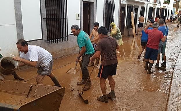 Imagen. Varios vecinos ayudan para quitar el barro tras la tormenta