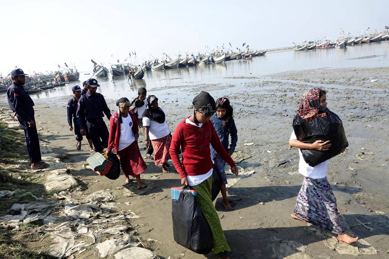 Policías birmanos escoltan al grupo de 106 rohinyás de vuelta a Sittwe en el estado de Rakáin (Birmania). El pasado 16 de noviembre, el barco en el que viajaban los 106 rohinyás encalló en la costa cerca de Rangún, con uno de sus ocupantes muerto, cuando trataba de llegar a Malasia. 