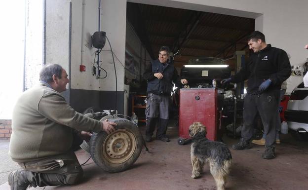 Juan Díaz y su hijo Alberto atienden a un cliente en su taller mecánico. :: 