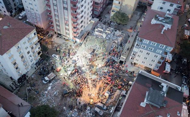 Varios efectivos de los equipos de rescate trabajan entre los escombros del edificio derrumbado en Estambul (Turquía).